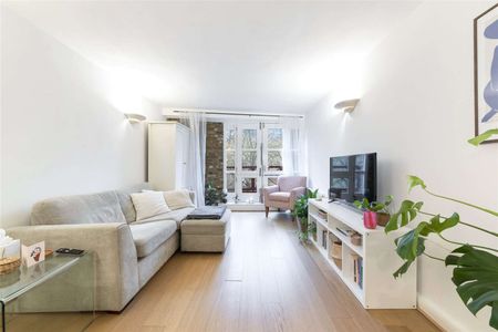 This property benefits from a bright and spacious reception room with exposed brickwork and wooden flooring. - Photo 4